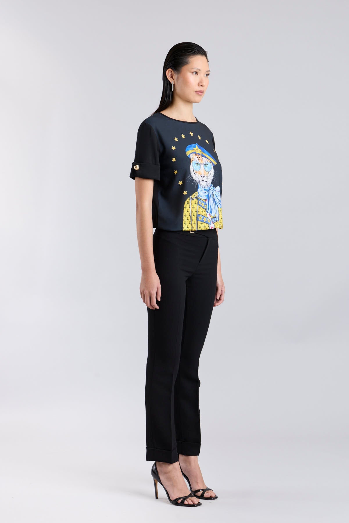 Camiseta negra con botones dorados en las mangas y estampado de tigre con boina azul de The Extreme Collection.