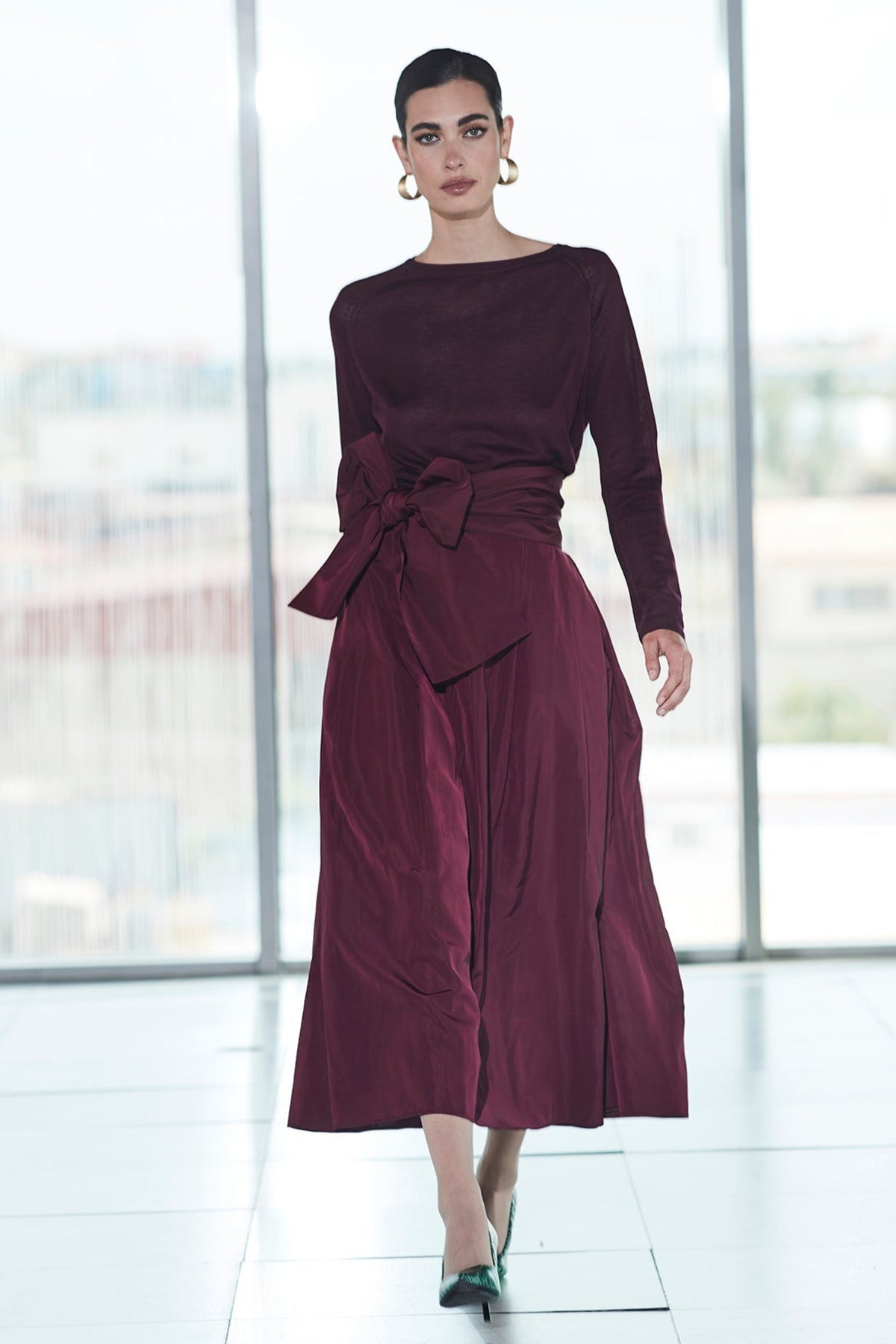Falda midi granate estructurada con volumen teatral, corte evasé y gran lazo sastre lateral. Alta costura, exclusividad y diseño artesanal hecho en España.