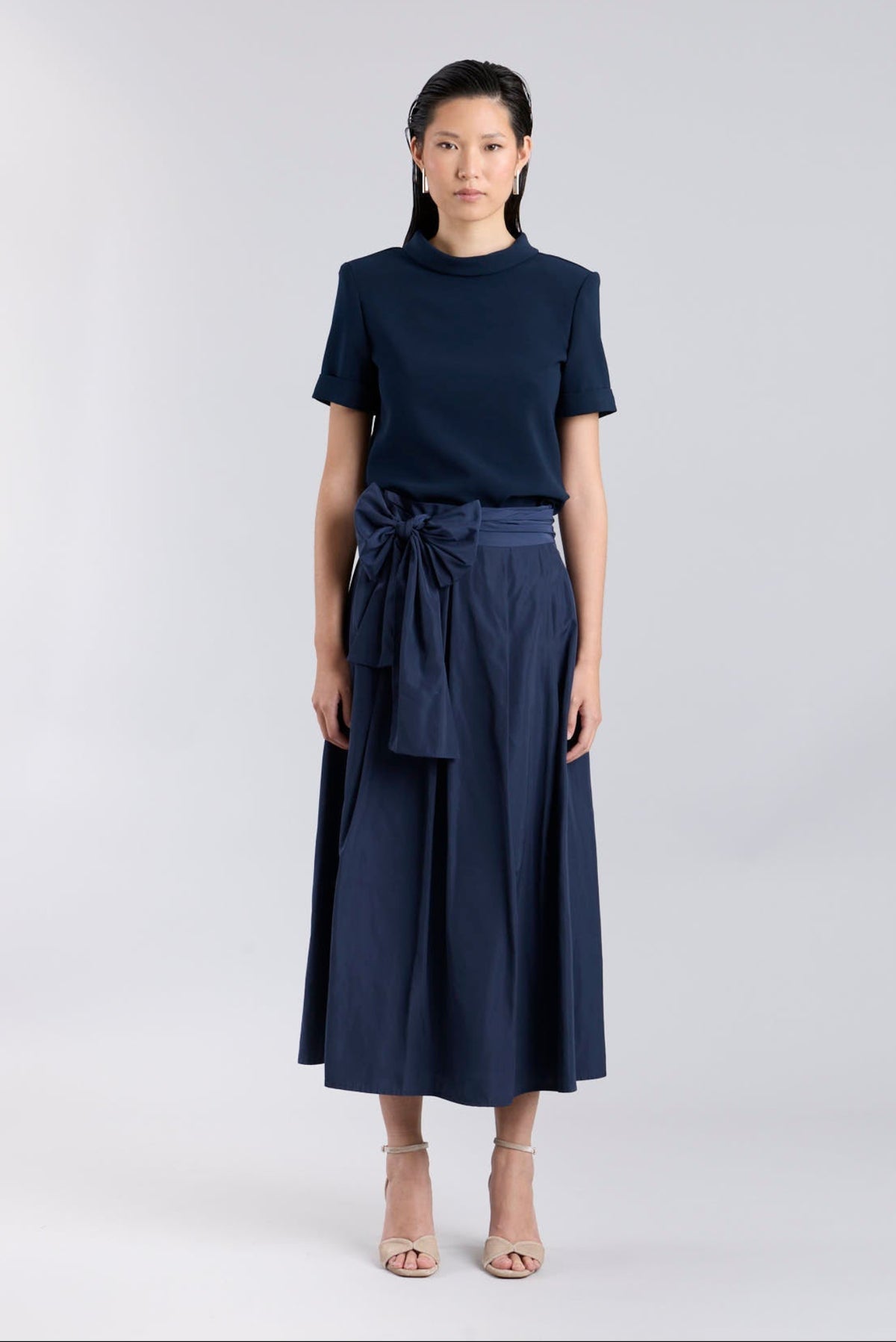 Falda midi marino estructuradacon volumen impecable, corte evasé y gran lazo sastre lateral. Alta costura, exclusividad y diseño artesanal hecho en España.
