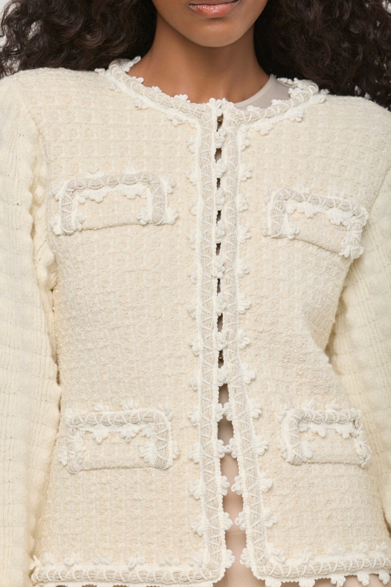 Cárdigan estructurado blanco de punto para mujer con estética estilo tweed, mangas abullonadas y ribetes detallados.