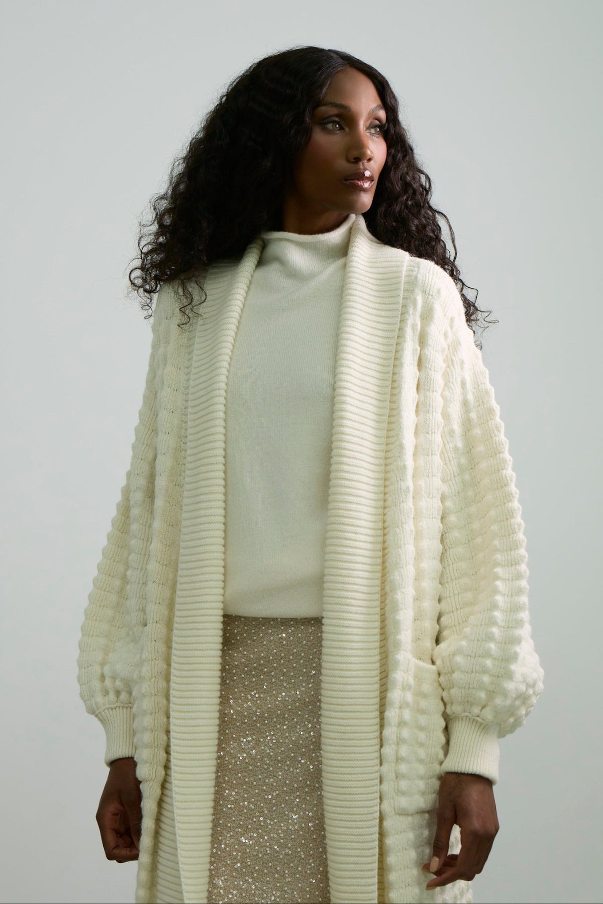 Cárdigan largo de punto blanco blanco para mujer con mangas de textura geométrica y diseño minimalista.