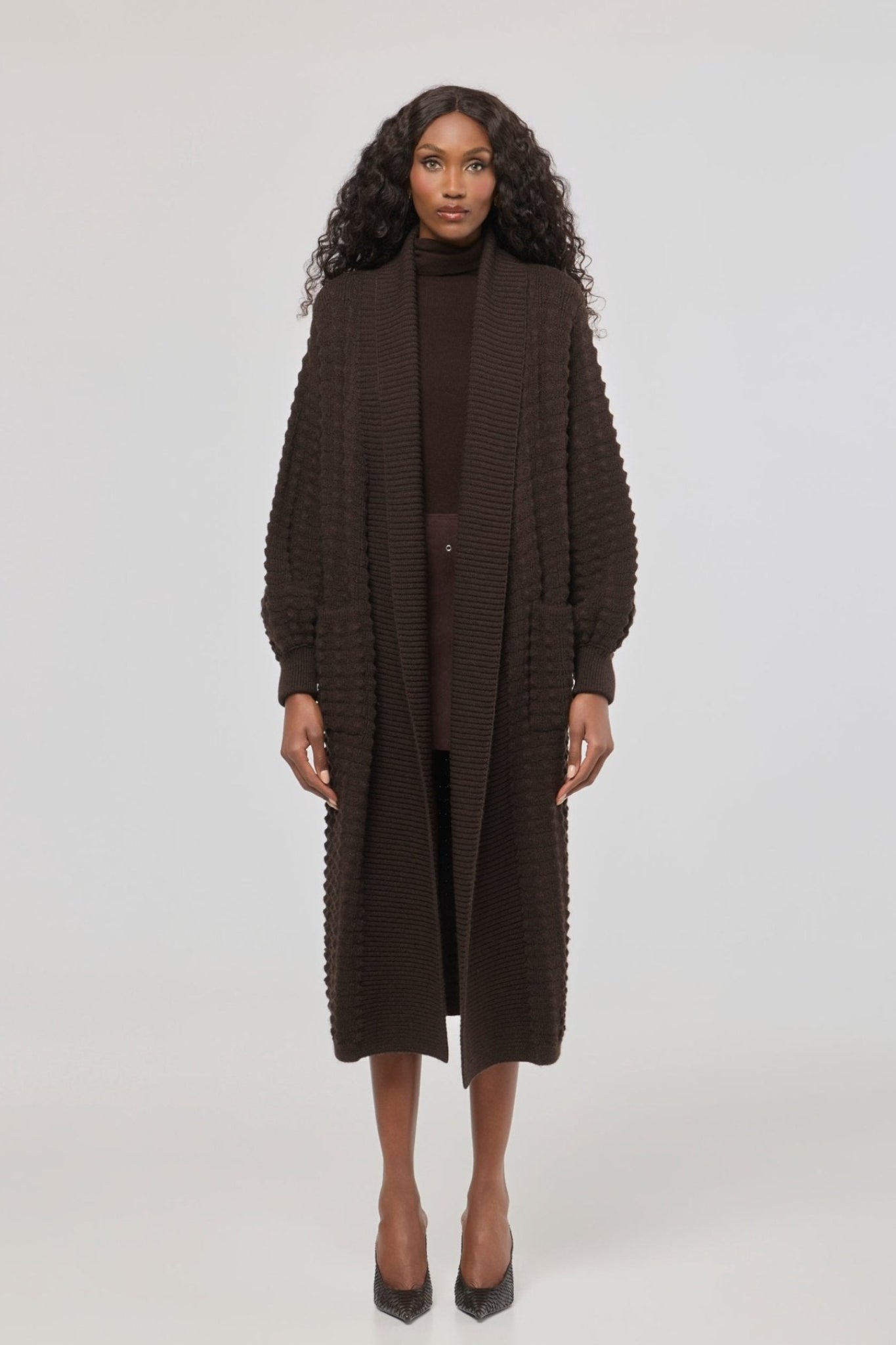 Cárdigan largo marrón de punto para mujer con mangas de textura geométrica y diseño minimalista.