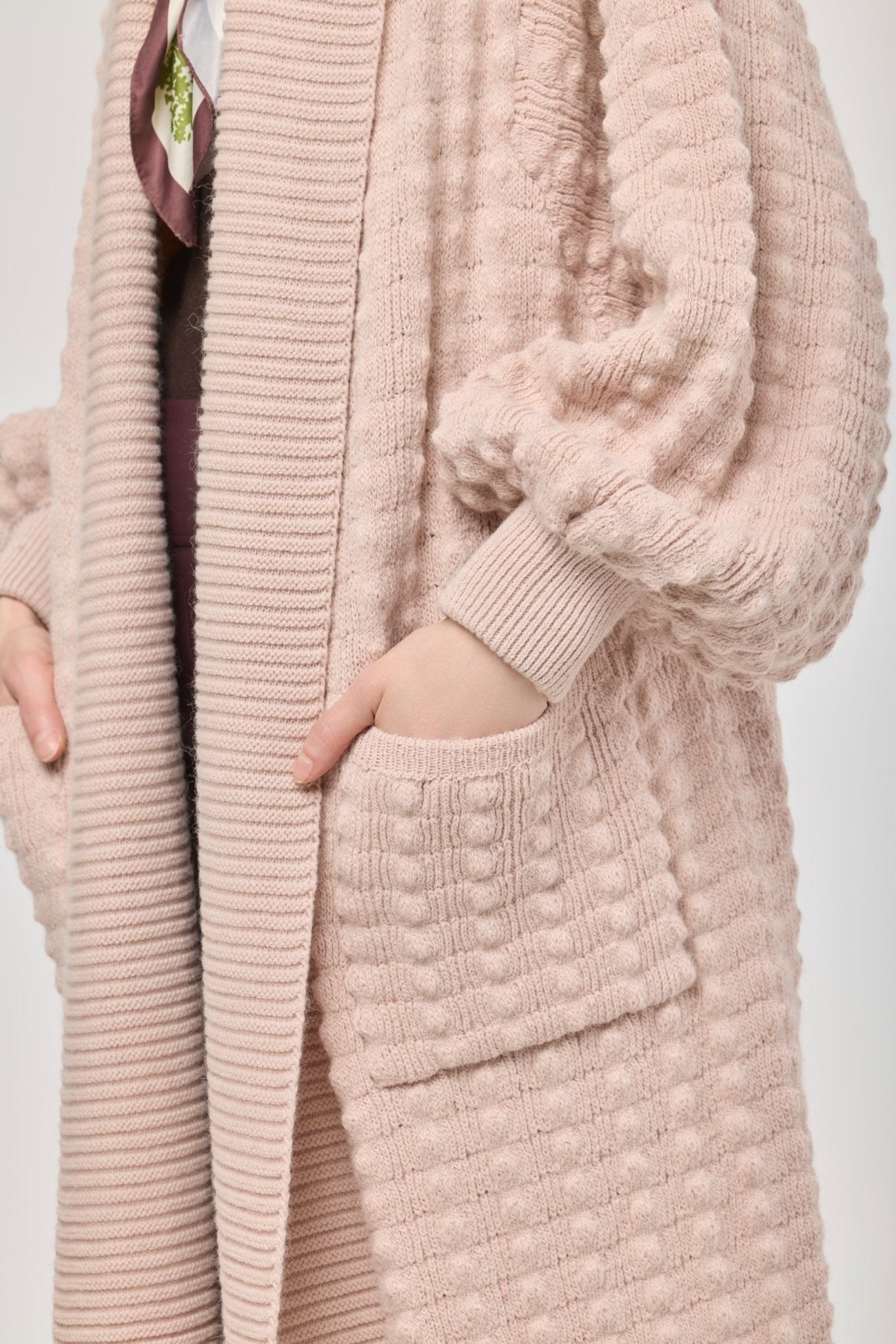 Cárdigan largo rosa de punto para mujer con mangas de textura geométrica y diseño minimalista.