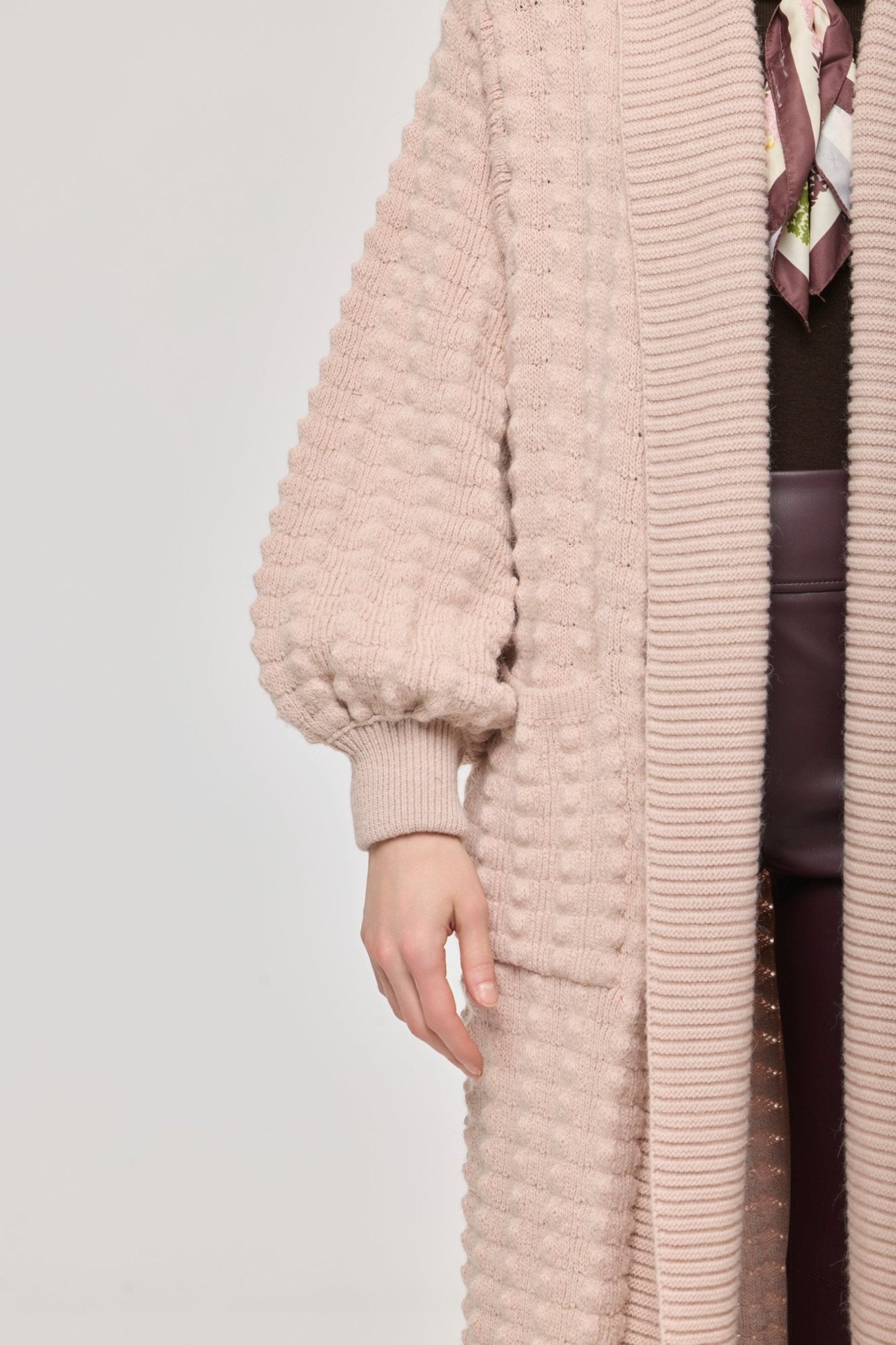 Cárdigan largo rosa de punto para mujer con mangas de textura geométrica y diseño minimalista.